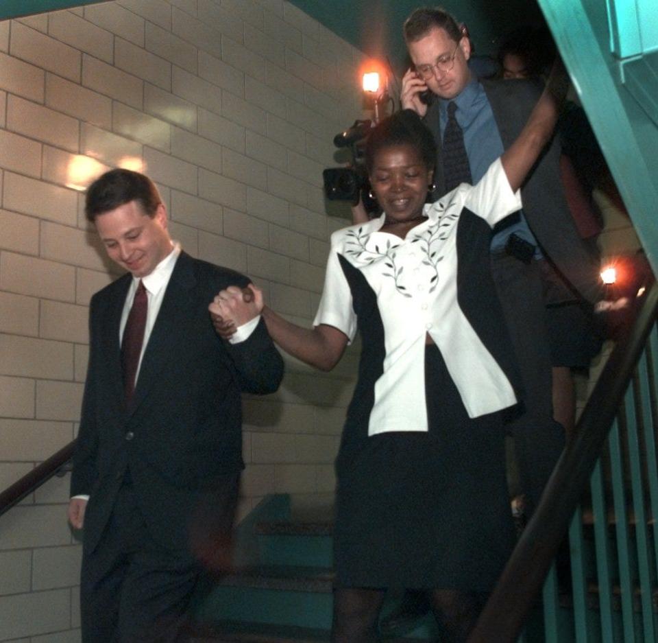 Betty Tyson holds the hands of her attorney, Jon Getz, as she heads down the back stairs of the Hall of Justice just after she was released from prison in 1998.