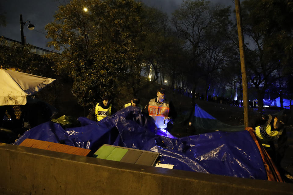 French police officers inspect migrants' tents as they clear an area Thursday, Nov. 7, 2019 in the north of Paris. Migrant encampments are becoming increasingly visible in the French capital. Police cleared Thursday several thousand people from a northern Paris neighborhood where migrants have repeatedly been removed. (AP Photo/Francois Mori)