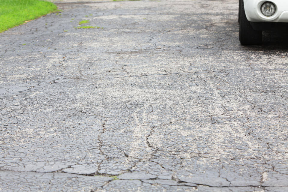 A paved asphalt driveway is cracked