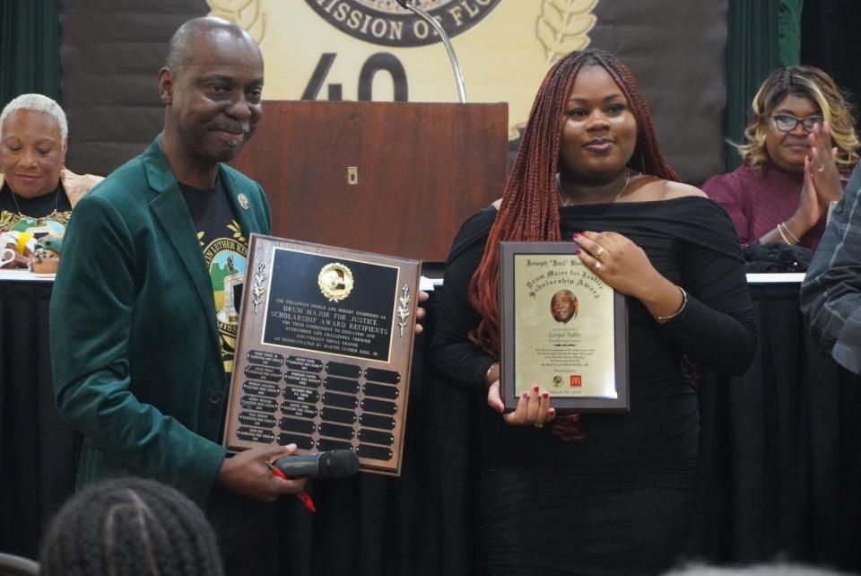 Rodney Long, MLK Commission of Florida Inc. president, poses with a plaque listing recipients of the Joseph “Joel” Buchanan Drum Major for Justice Scholarship Award. He stands next to this year’s recipient, Garyel Tubbs, a senior at Eastside High School in the International Baccalaureate program.