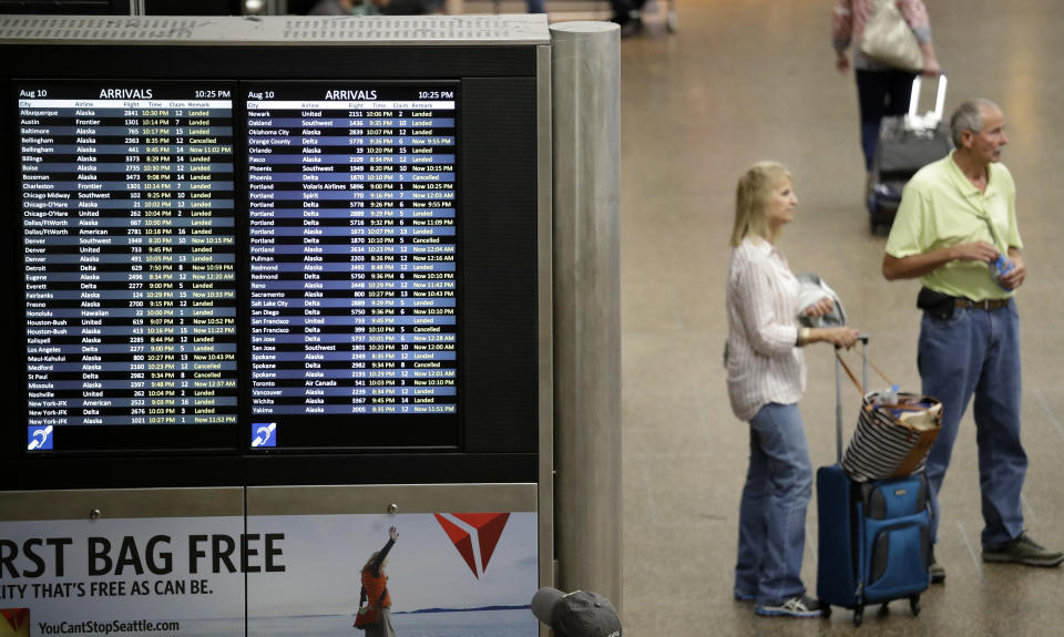 People wait near the luggage area at Sea-Tac International Airport Friday, Aug. 10, 2018, in SeaTac, Wash. An airline mechanic stole an Alaska Airlines plane without any passengers and took off from Sea-Tac International Airport in Washington state on Friday night before crashing near Ketron Island, officials said. (AP Photo/Elaine Thompson)