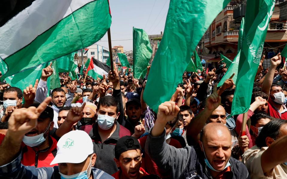 Hamas supporters wave green Islamic flags while chant slogans during a rally in solidarity with fellow Palestinians in Jerusalem and against Palestinian President Mahmoud Abbas decision to postpone Palestinian elections, in Jebaliya refugee camp, Gaza Strip - Adel Hana /AP