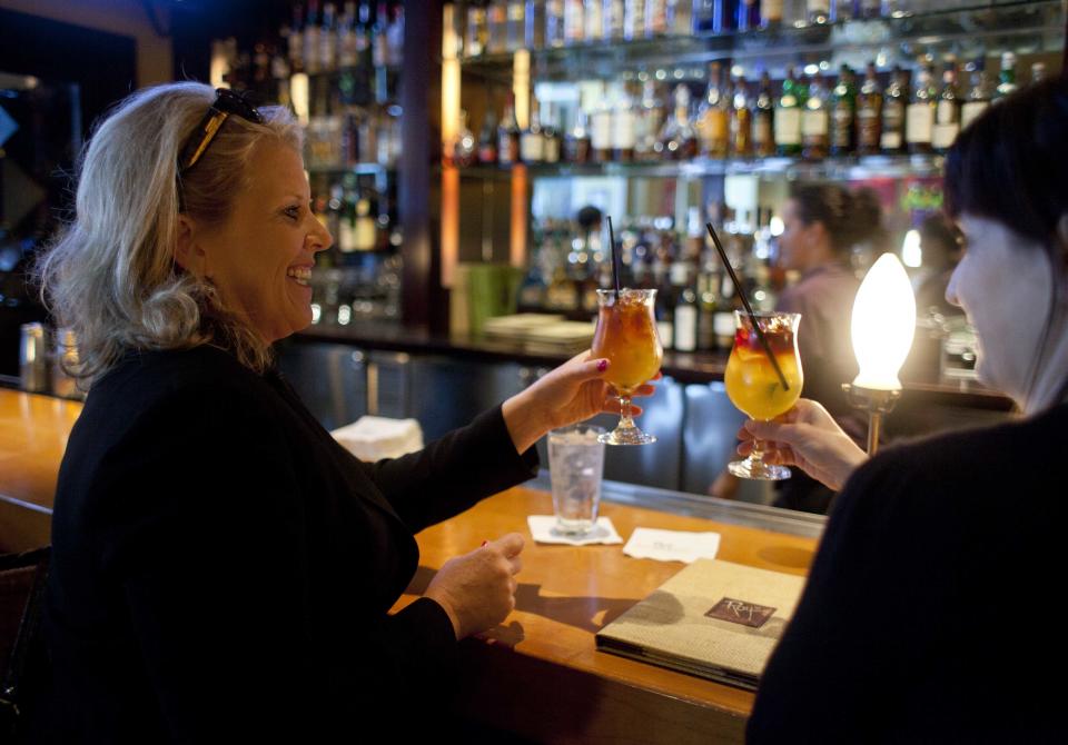 In this photo taken Monday, Aug. 6, 2012, Melissa Fullerton, left, of Highland Village, Tex., raises her $5 Mai Tai during happy hour at the Roy's restaurant in San Francisco. The concept of happy hour when bars offer lower prices or two-for-one specials seems like a widespread tradition, but is actually illegal or restricted in quite a few places. (AP Photo/Eric Risberg)