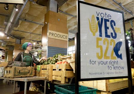 An employee stocks produce near a sign supporting a ballot initiative in Washington state that would require labeling of foods containing genetically modified crops at the Central Co-op in Seattle, Washington October 29, 2013. REUTERS/Jason Redmond