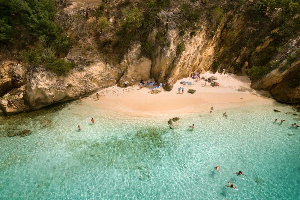 Aerial view of people on a beach below a sheer cliff in Anguilla