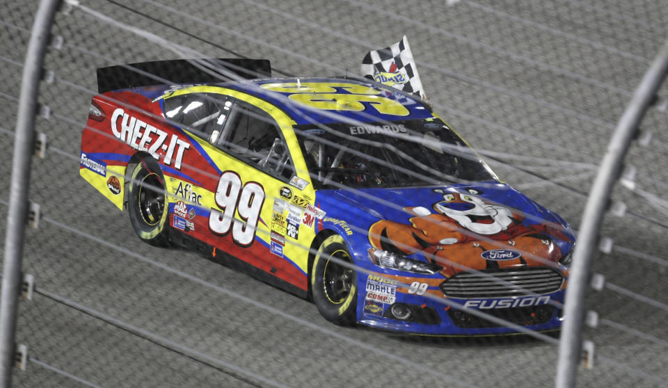 FILE - Carl Edwards takes the checkered flag around the track as he celebrates winning the NASCAR Sprint Cup Series auto race at Richmond International Raceway in Richmond, Va., Saturday, Sept. 7, 2013. Edwards, one of NASCAR’s top 75 drivers, was elected to the NASCAR Hall of Fame last week based on his 28 career Cup victories. He said his election to the Hall was a surprise he didn’t see coming. (AP Photo/Jason Hirschfeld, File)