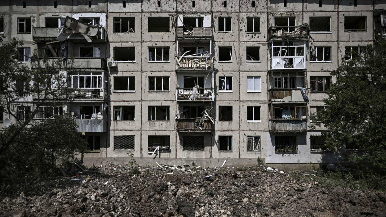 A picture shows a crater in front of a damaged apartment building after a missile strike in the city of Soledar, in the eastern Ukrainian region of Donbas on June 4, 2022. - Russian artillery is slamming Ukraine's eastern Donbas region with fierce fighting over the city of Severodonetsk, but the local governor says there was some progress in pushing back invading forces. (Photo by ARIS MESSINIS / AFP)