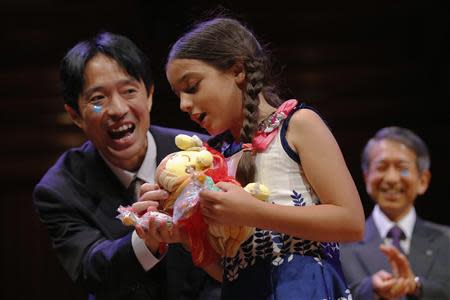 Muneaki Tomotake (L), of Japan, presents gifts to Miss Sweetie Poo, played by Sharanda Sundaram-Senders, as Tomotake and his colleagues accepted the 2013 chemistry prize during the 23rd First Annual Ig Nobel Prize ceremony at Harvard University in Cambridge, Massachusetts September 12, 2013. REUTERS/Brian Snyder