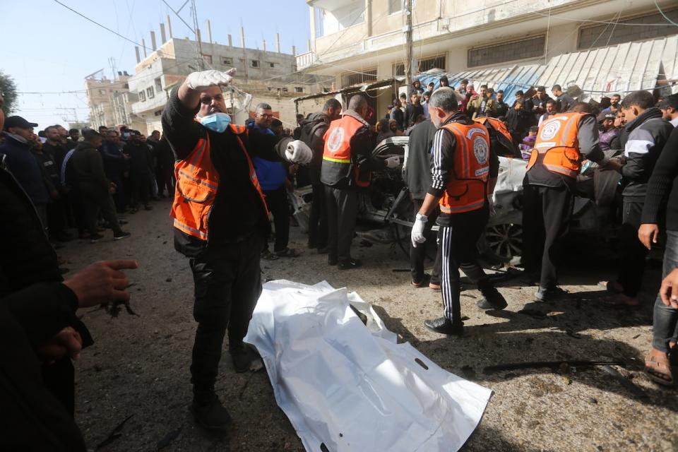 Palestinians evacuate the body of a person killed in an Israeli airstrike on a car in Rafah, Gaza Strip, Friday, Dec. 22, 2023.