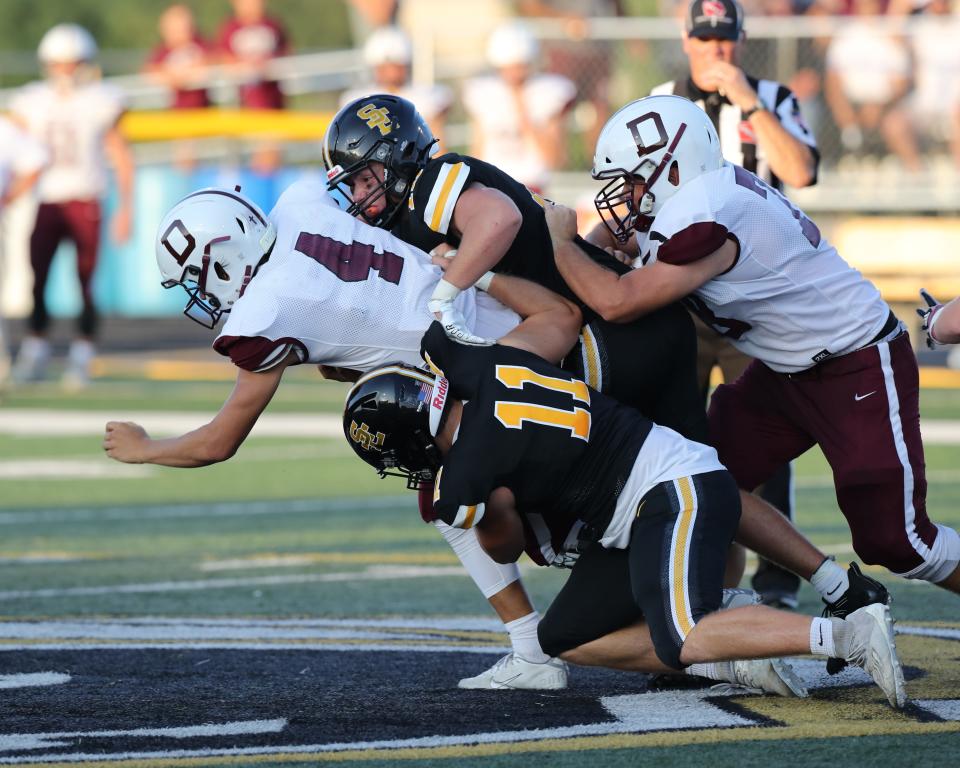 Southeast Polk's Andrew Reed (32) and Andrew Harris (11) tackle Dowling Catholic's Jaxon Smolik (4) during a game on Friday, Aug. 27, 2021