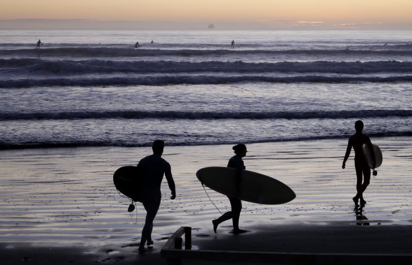 Surfers prepare to enter the water at Sumner Beach as level four COVID-19 restrictions are eased in Christchurch, New Zealand, Tuesday, April 28, 2020. New Zealand eased its strict lockdown restrictions to level three at midnight to open up certain sections of the economy but social distancing rules will still apply. (AP Photo/Mark Baker)