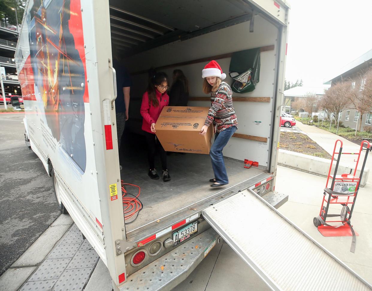 Kidzz Helping Kidzz advisory board members Anabelle Perez, 12, and Selah Guy, 12, carry a box of donated toys as they help unload the truck at St. Michael Medical Center in Silverdale on Thursday, Dec. 21, 2023.