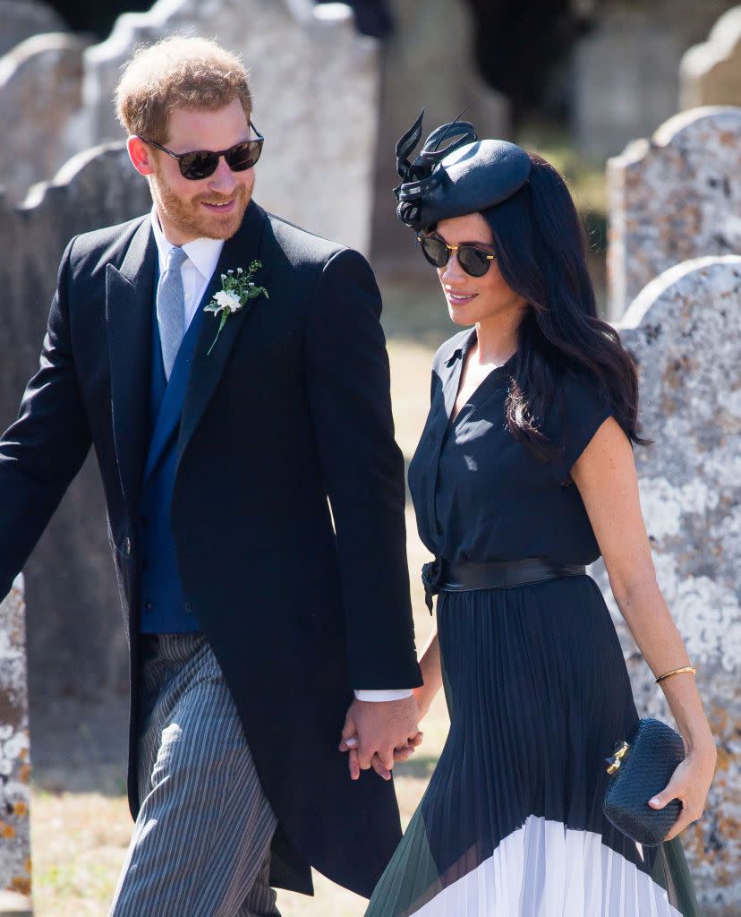 Harry and Meghan hold hands while arriving at a wedding.