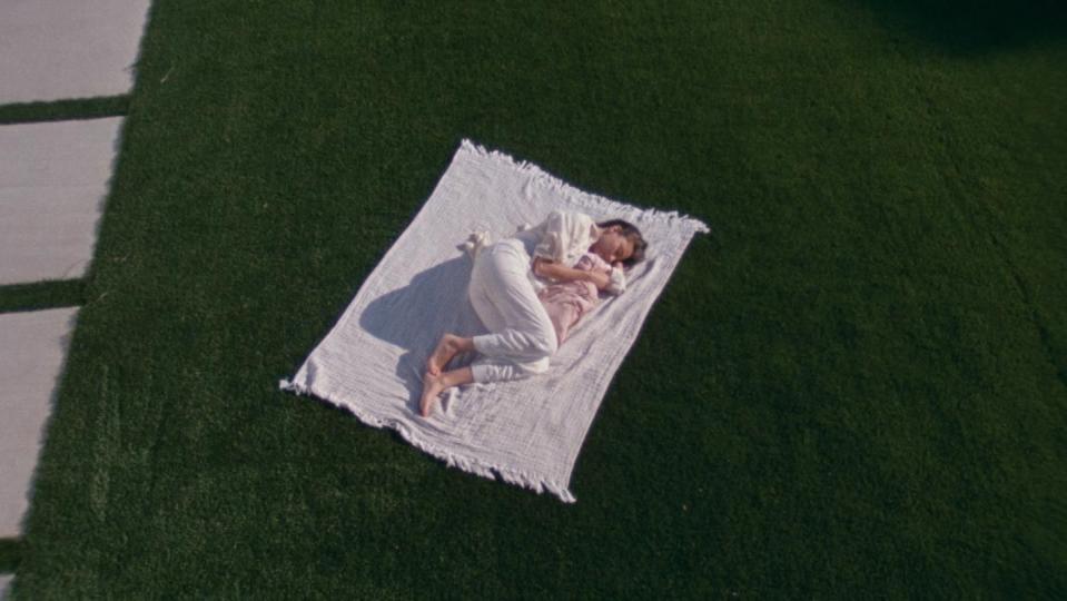 a person lying on a white sheet on grass