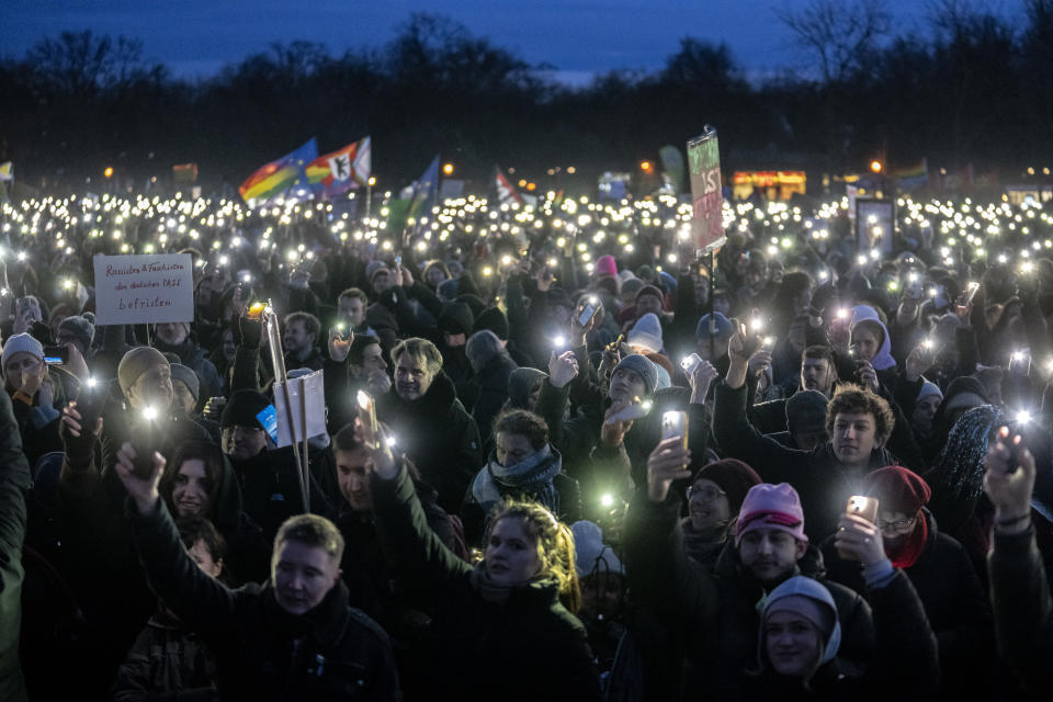 People hold up their cell phones as they protest against the AfD party and right-wing extremism in front of the Reichstag building in Berlin, Germany, Sunday, Jan. 21, 2024. (AP Photo/Ebrahim Noroozi)