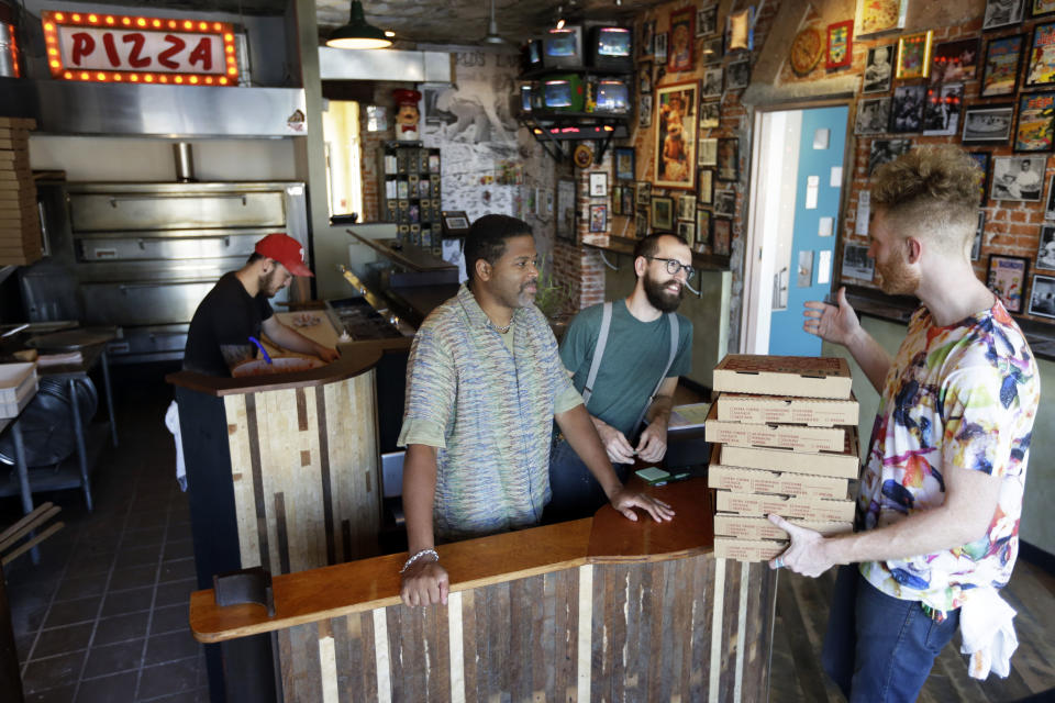 In this Wednesday, Sept. 12, 2012 photo, the owners of Pizza Brain, from left, Joseph Hunter, Michael Carter, Ryan Anderson, and Brian Dwyer work the storefront in Philadelphia. Hundreds of people turned out for the grand opening of Pizza Brain this month in Philadelphia's Fishtown neighborhood. It's a restaurant where visitors can eat a slice or two of artisan pie while gawking at a pizza-related photos, records, knickknacks and videos. Though only a portion of the massive collection is on display, Dwyer says the items will be rotated so there's always something new to see.(AP Photo/Matt Rourke)