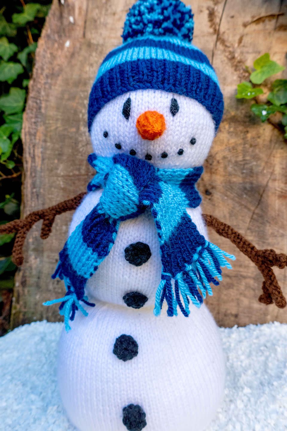 a knitted snowman with a blue hat and scarf