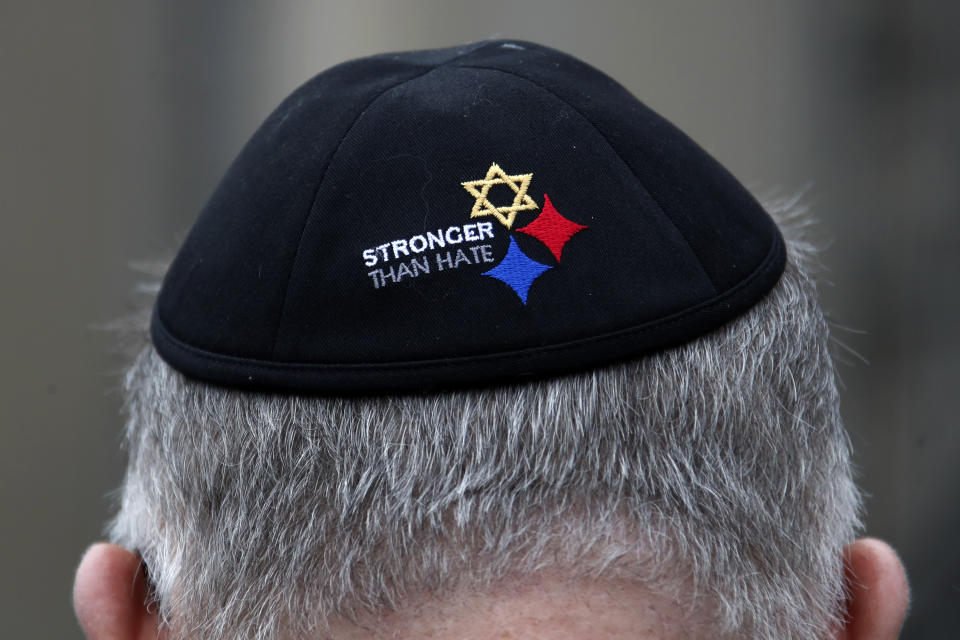 FILE - In this Sunday, Oct. 27, 2019 file photo, a man wearing a "Stronger Than Hate" yarmulke stands outside the Tree of Life synagogue in Pittsburgh on the first anniversary of the shooting at the synagogue, that killed 11 worshippers. On Tuesday, Oct. 27, 2020, as they again mourn those killed two years earlier, they’ll also celebrate the resilience that has enabled them to persevere. (AP Photo/Gene J. Puskar)