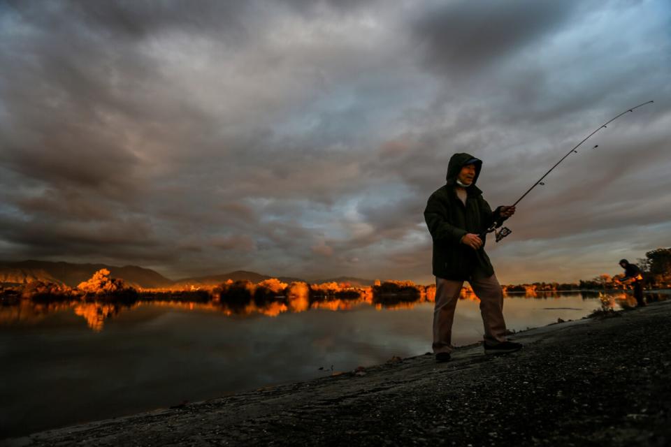 Ying Ten finishes a day of fishing Tuesday as the sun sets with Santa Fe Dam aglow.