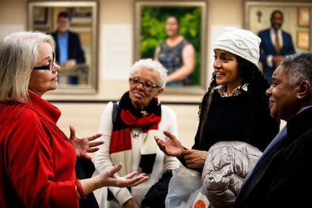 Artist Betsy Ashton discusses with visitors her work process for her exhibition, "Portraits of Immigrants: Unknown Faces, Untold Stories" at Riverside Church in New York, U.S., March 10, 2019. REUTERS/Demetrius Freeman