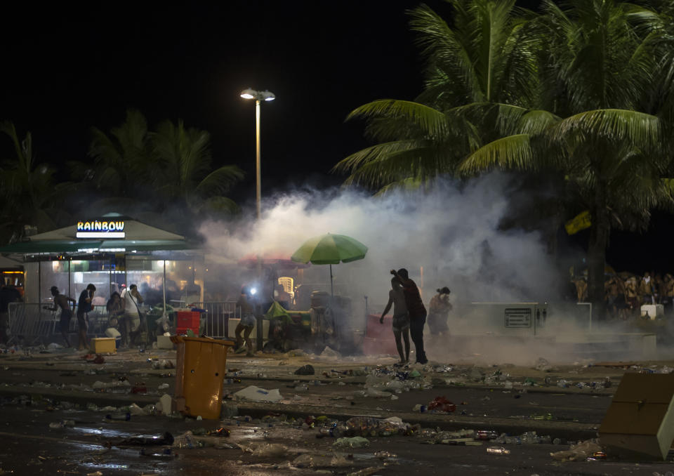 Police officers throw tear gas during clashes with party-goers after the official start of Carnival, on Copacabana beach, Rio de Janeiro, Brazil, Sunday, Jan. 12, 2020. Police officers and municipal guards dispersed attendees with gas bombs, and moments of tension were experienced in the deconcentration of the event, which brought together hundreds of thousands of people. (AP Photo/Bruna Prado)