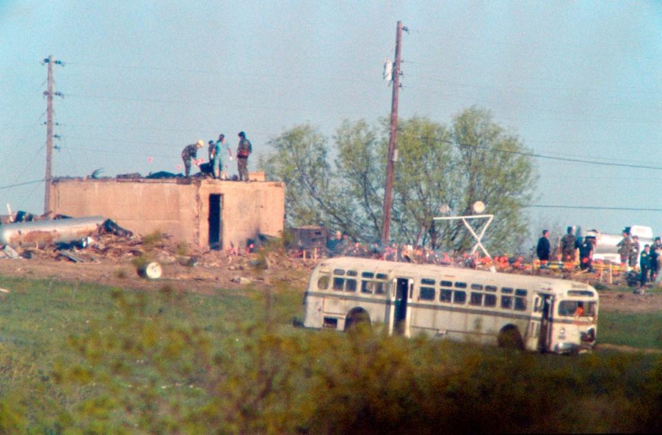 Texas Department of Safety Investigators and medical examiners search the rubble of the burnt-out Branch Davidian compound and mark body locations with small flags on 22 April 1993 in Waco (J DAVID AKE/AFP via Getty Images)