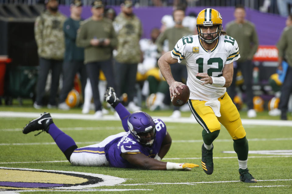 Green Bay Packers quarterback Aaron Rodgers (12) runs from Minnesota Vikings defensive tackle Dalvin Tomlinson (94) during the second half of an NFL football game, Sunday, Nov. 21, 2021, in Minneapolis. (AP Photo/Bruce Kluckhohn)