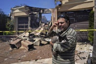 Sassan Darian holds his cat Cyrus as he stands in front of his family's fire-damaged home in the aftermath of the Coastal Fire Thursday, May 12, 2022, in Laguna Niguel, Calif. (AP Photo/Marcio Jose Sanchez)