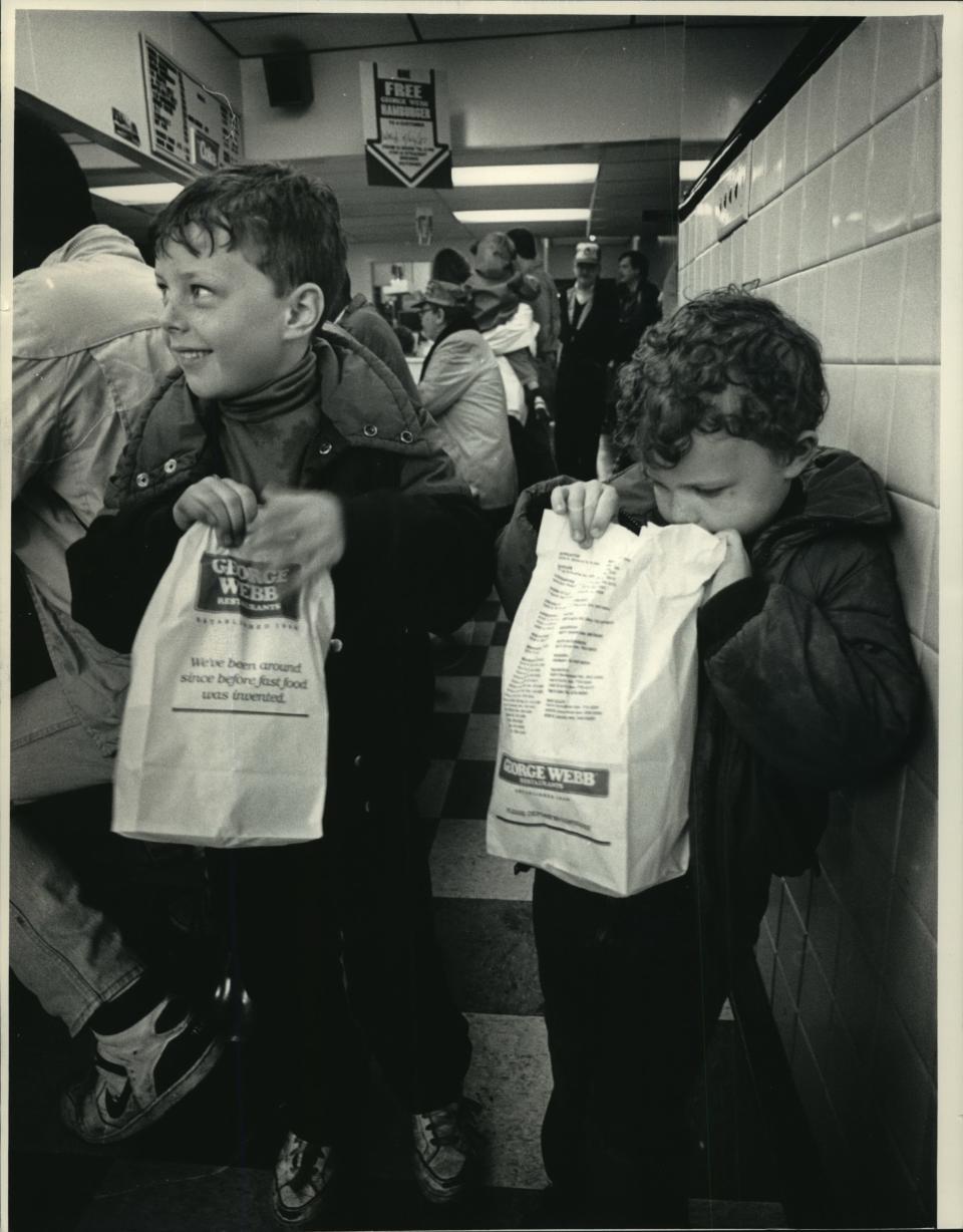 Sean Harper, 6, and his brother, Brett, 4, left George Webb restaurant in Shorewood with their historic hamburgers safely bagged in 1987 after the Brewers won 12 straight games. A crowd squeezed around the counter and along the wall waiting for their burgers.