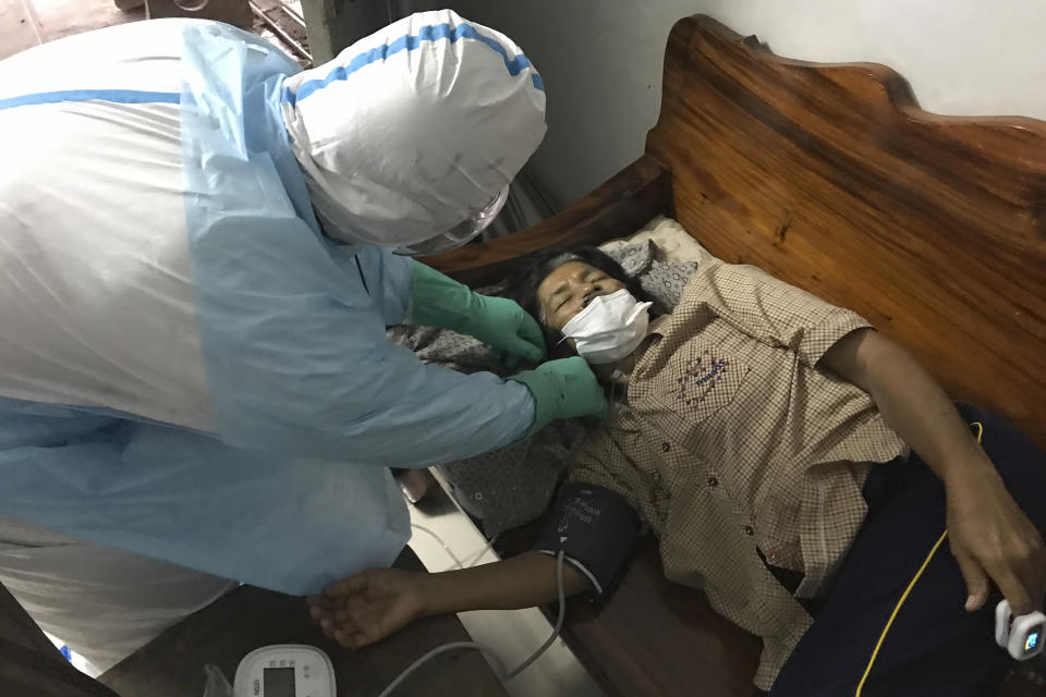 A volunteer from the 'Saimai Will Survive' group in protective gear adjusts an oxygen line to help a woman infected with COVID-19 with difficulty breathing at her home, Friday, July 23, 2021, in Bangkok, Thailand. As Thailand's medical system struggles beneath a surge of coronavirus cases, ordinary people are helping to plug the gaps, risking their own health to bring care and supplies to often terrified, exhausted patients who've fallen through the cracks. (AP Photo/Tassanee Vejpongsa)