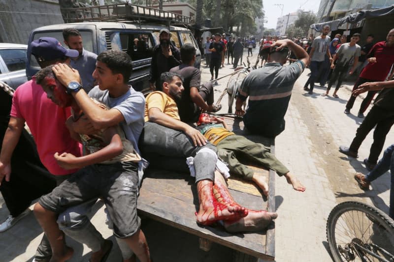 Injured Palestinians are transported from a school after it was hit by an Israeli strike, in Deir el-Balah in the central Gaza Strip. Omar Ashtawy/APA Images via ZUMA Press Wire/dpa