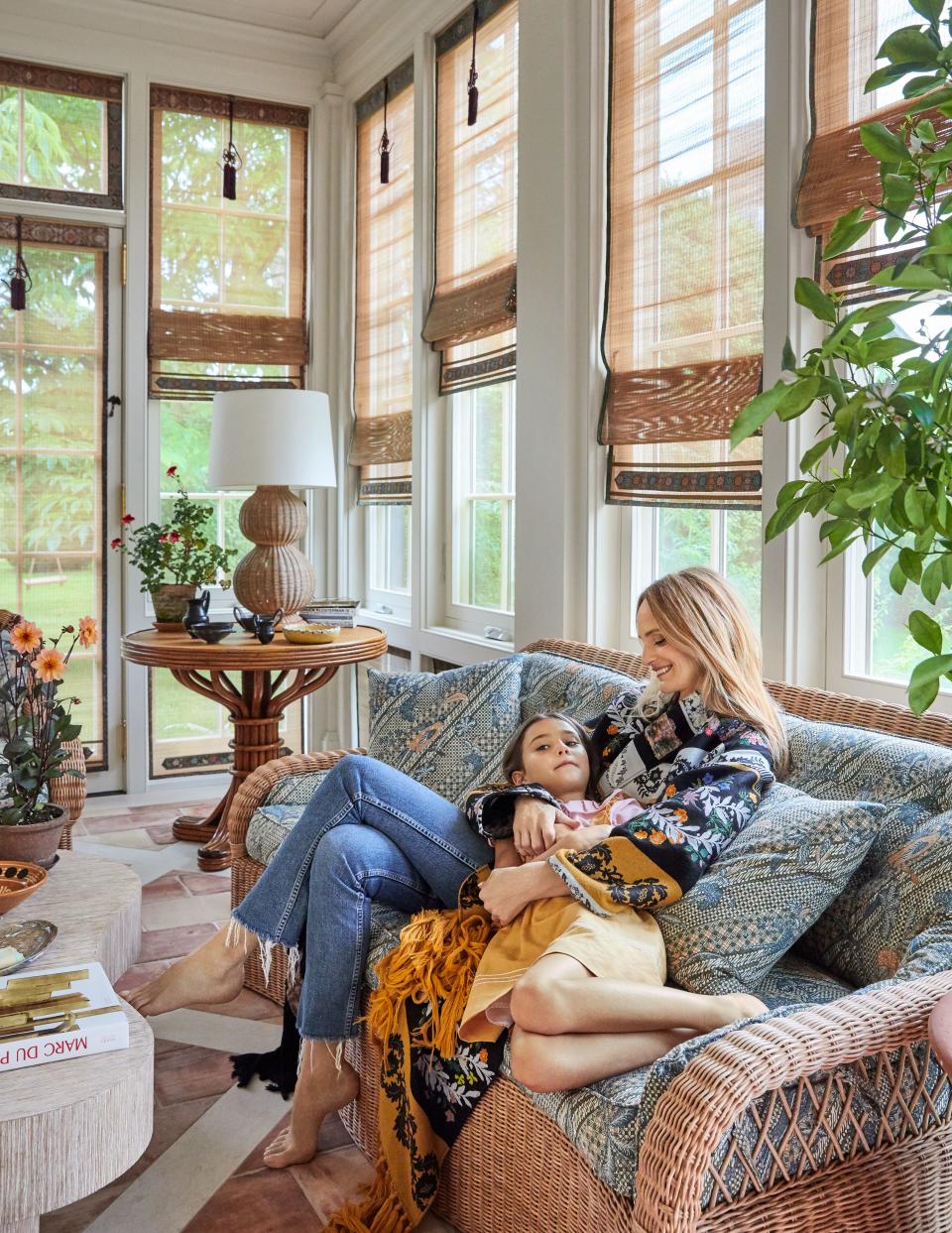 Santo Domingo (wearing an Oscar de la Renta coat) and her daughter, Beatrice, snuggle up on the sunporch. With its Lilou Marquand rattan shades, it doubles as a cozy dining room in inclement weather.