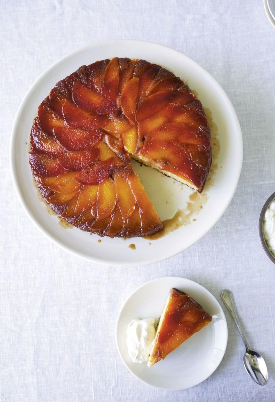 peach upside down cake on a white plate with a slice on a small plate next to it with a dollop of whipped cream