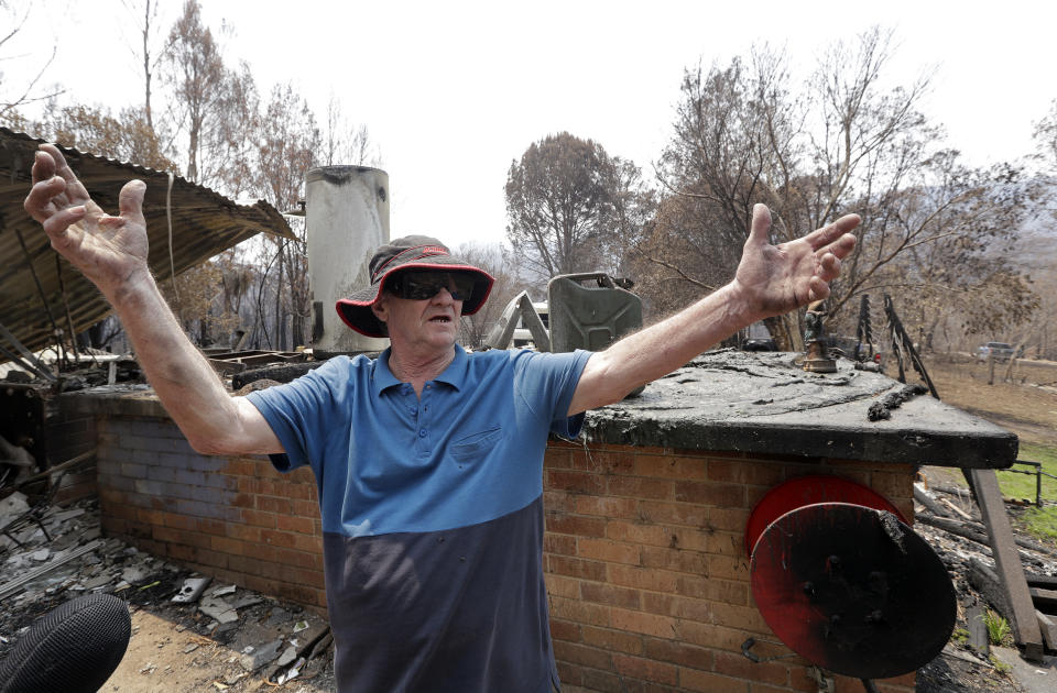 Colin Brennan stands in the debris of his destroyed house lost in the New Year's Eve wildfire at Nerrigundah, Australia, Monday, Jan. 13, 2020. The tiny village of Nerrigundah in New South Wales has been among the hardest hit by Australia's devastating wildfires, with about two thirds of the homes destroyed and a 71-year-old man killed. (AP Photo/Rick Rycroft)