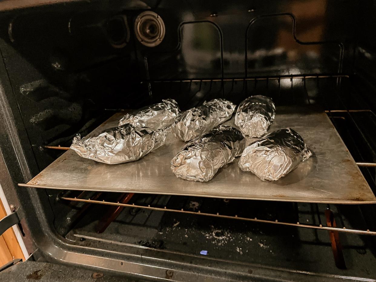 baked potatoes wrapped in foil in an oven