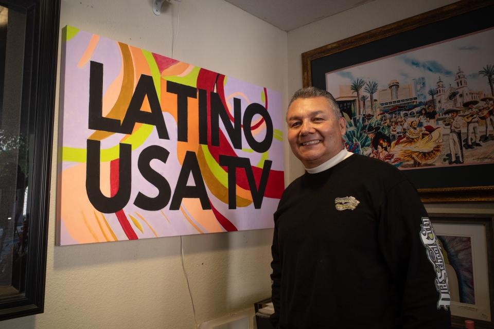 Gil Bivens, founder of Arizona Barrio Stories, poses in front of a sign for Latino USA TV. A recent acquisition of the Roku channel has allowed Bivens and his team to share their original content with nationwide audiences.