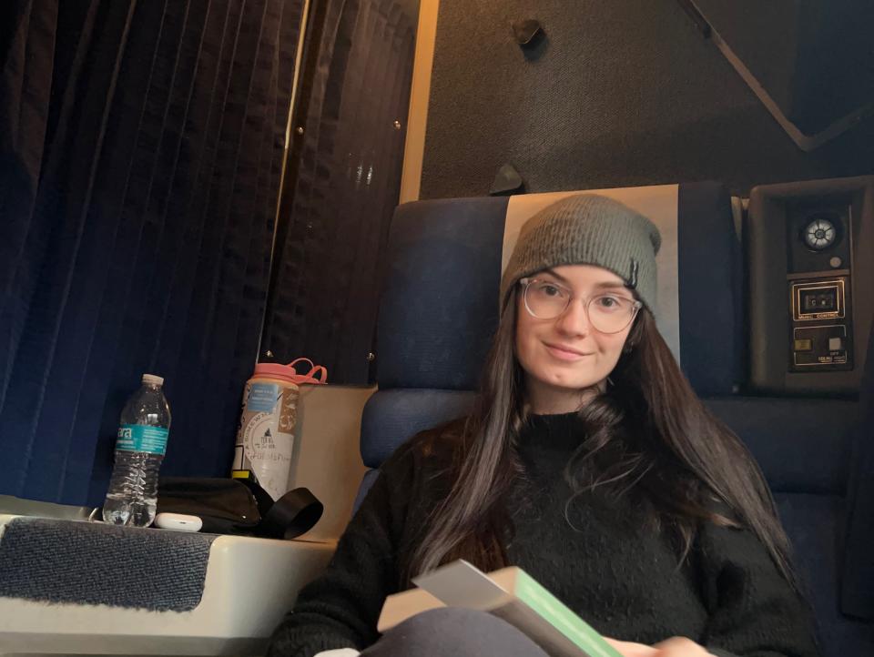 The author holding a book, sitting in a seat in her Amtrak roomette.