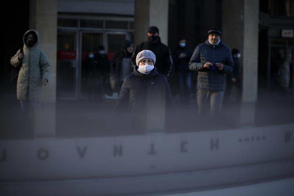 A woman wearing a face mask to help curb the spread of the coronavirus walks into the underpass under the street during sunset in Moscow, Russia, Wednesday, Dec. 2, 2020. Russia has registered a record number of coronavirus deaths for a second straight day. Currently, there is a country-wide mask mandate and mostly mild restrictions that vary from region to region. (AP Photo/Alexander Zemlianichenko)