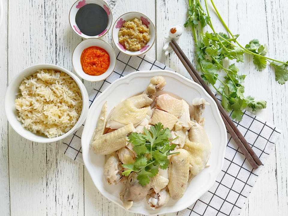 chicken with cilantro as a garnish on white plate next to bowl of white rice