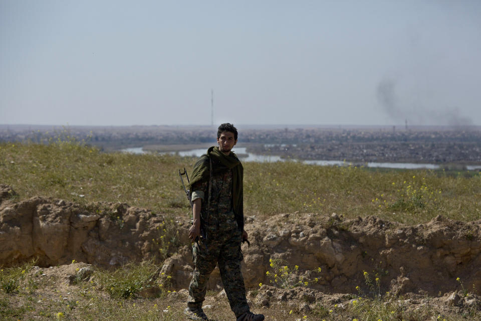 A U.S.-backed Syrian Democratic Forces (SDF) soldier walks on a hilltop overlooking Baghouz, Syria, Wednesday, March 20, 2019. (AP Photo/Maya Alleruzzo)