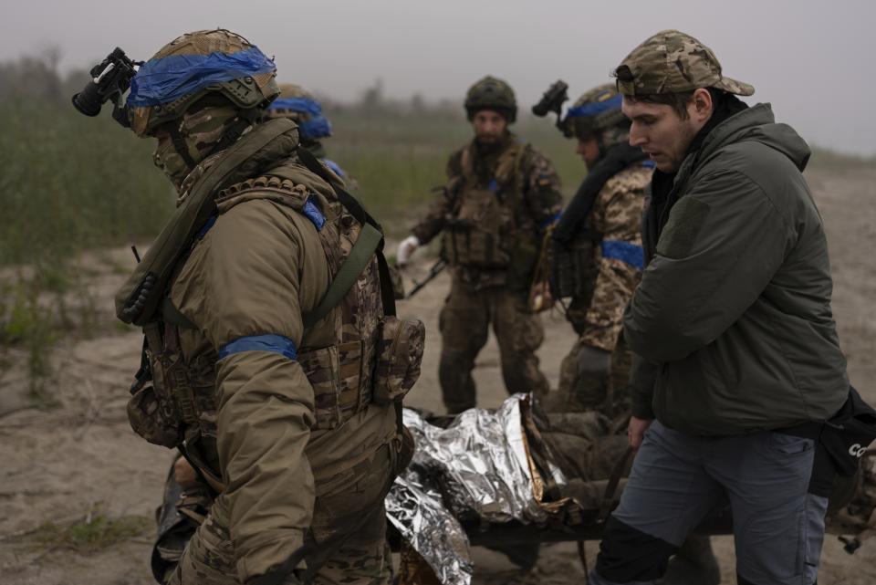 FILE - Ukrainian servicemen evacuate injured comrade at the frontline close to the Dnipro near Kherson, Ukraine, on Oct. 14, 2023. Two years after Russia’s full-scale invasion captured nearly a quarter of the country, the stakes could not be higher for Kyiv. After a string of victories in the first year of the war, fortunes have turned for the Ukrainian military, which is dug in, outgunned and outnumbered against a more powerful opponent. (AP Photo/Alex Babenko, File)