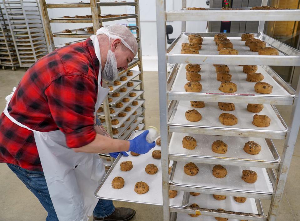 D'VINE Cookies quality assurance manager Joe Hutchinson sprinkles kosher sea salt to chocolate chip cookies to be baked in an oven at the industrial facility of D'VINE Cookies in Taylor on January 4, 2023.