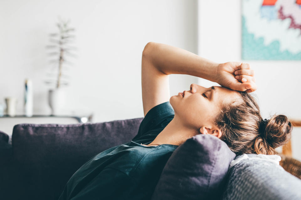 Woman resting arm on head on her sofa.