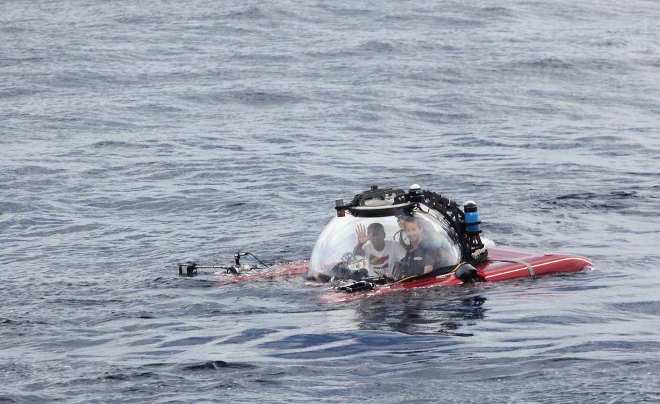 Seychelles President Danny Faure waves as he emerges from the ocean inside a submersible, off the coast of Seychelles on Sunday April 14, 2019. In a striking speech delivered from deep below the ocean's surface, the Seychelles president on Sunday made a global plea for stronger protection of the "beating blue heart of our planet." President Danny Faure's call for action, the first-ever live speech from an underwater submersible, came from one of the many island nations threatened by global warming.(AP Photo/Steve Barker)