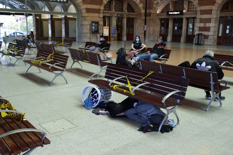 A homeless man sleeps under a bench at Sydney Central railway station during a workday following the implementation of stricter social-distancing and self-isolation rules to limit the spread of the coronavirus disease (COVID-19)