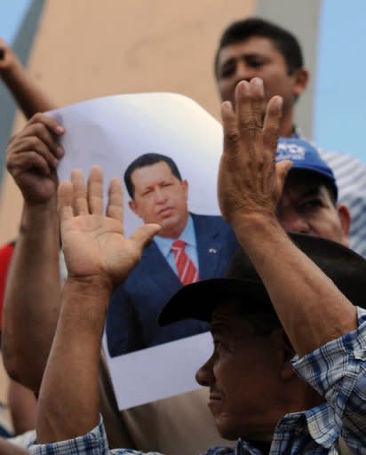 Seguidoresa de Chávez en Honduras sostienen fotos del mandatario durante una actividad para pedir por su recuperación.