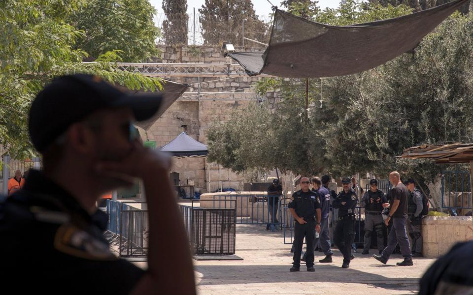 Israeli policeman guarding outside Lions' Gate, the main the entrance to the al-Aqsa compound next to the metal detectors, and a new cameras installed (top of the picture), as part of the new security measures - Credit: EPA