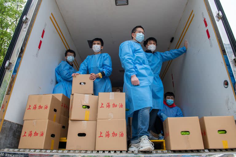 Voluntarios de la comunidad se preparan para entregar cajas de alimentos que son distribuidos por el gobierno local a los residentes en un complejo durante un cierre de Covid-19, en el distrito de Pudong en Shanghai el 15 de abril de 2022.