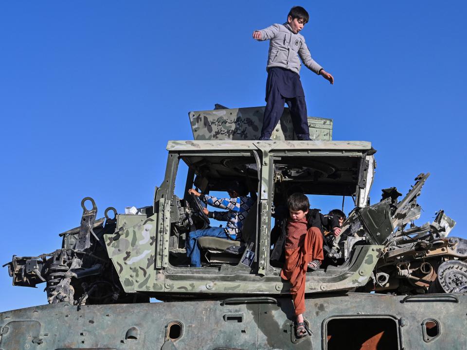 In this picture taken on November 13, 2021, boys play on a destroyed armoured vehicle displayed along a road in Ghazni.