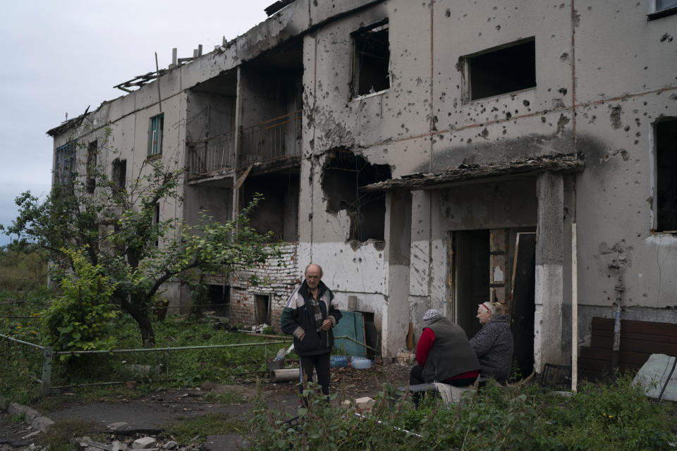 Oleh Lutsai, 70, stands with his neighbors at the entrance of their damaged residential building in the freed village of Hrakove, Ukraine, Tuesday, Sept. 13, 2022. Russian troops occupied this small village southeast of Ukraine’s second largest city of Kharkiv for six months before suddenly abandoning it around Sept. 9 as Ukrainian forces advanced in a lightning-swift counteroffensive that swept southward. (AP Photo/Leo Correa)
